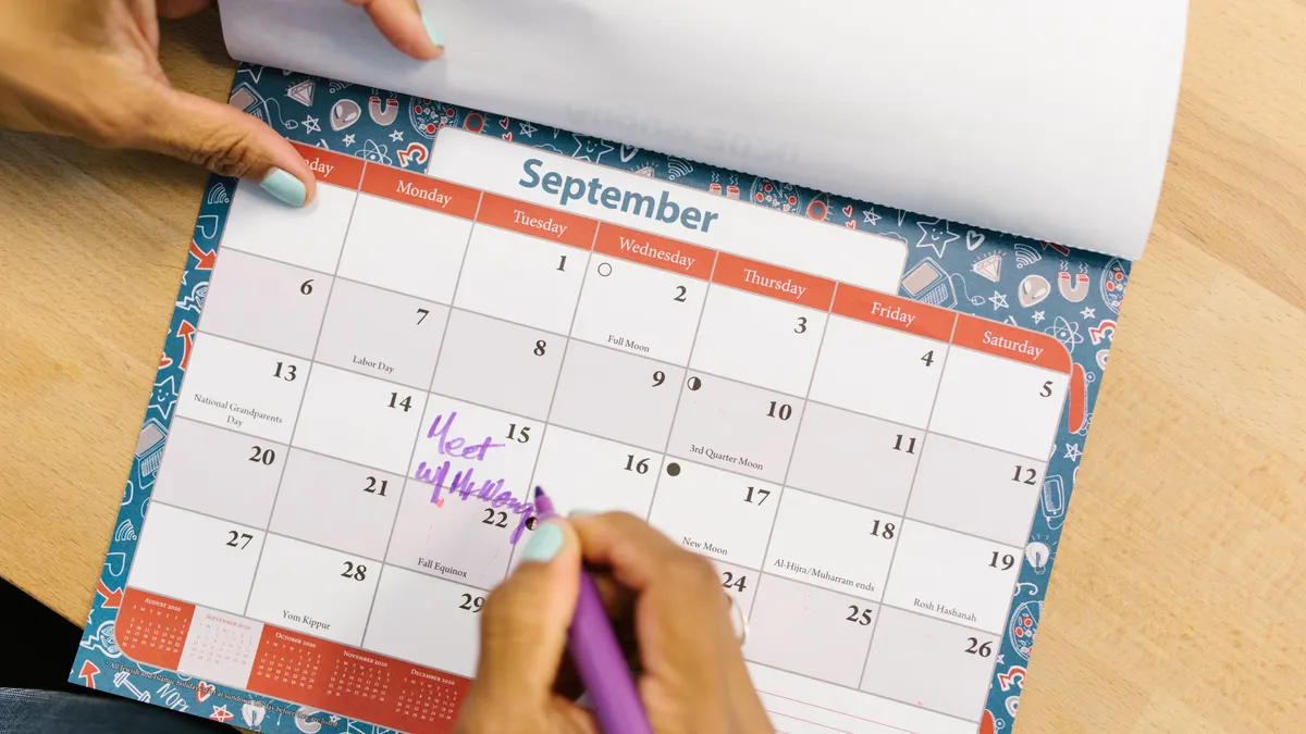 Hands marking a September calendar page